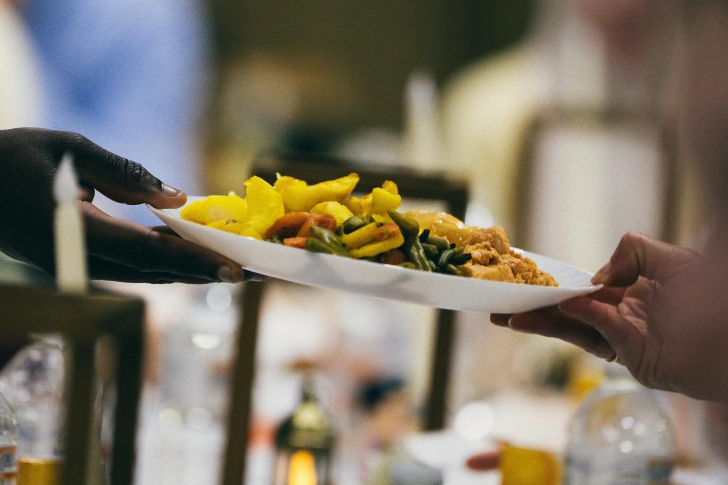Een bord eten wordt doorgegeven aan een gedekte iftar-tafel